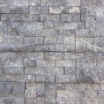 A stone wall with many different blocks of grey.